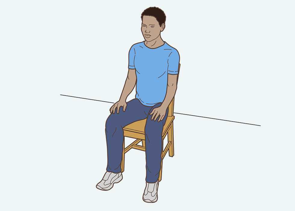 अपनी जांघों पर हाथ रखकर व्यक्ति कुर्सी पर बैठा है।